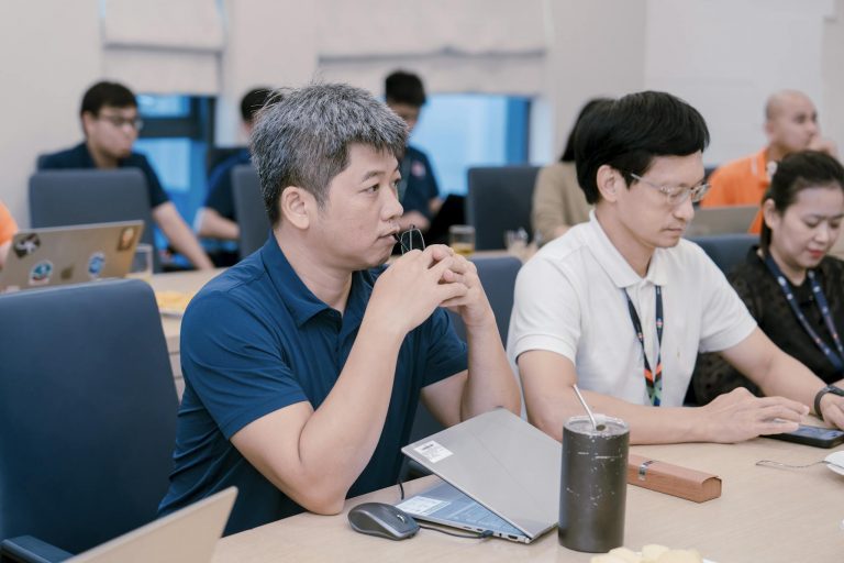 Engaged professionals in a corporate meeting room discussing ideas with laptops and notes.
